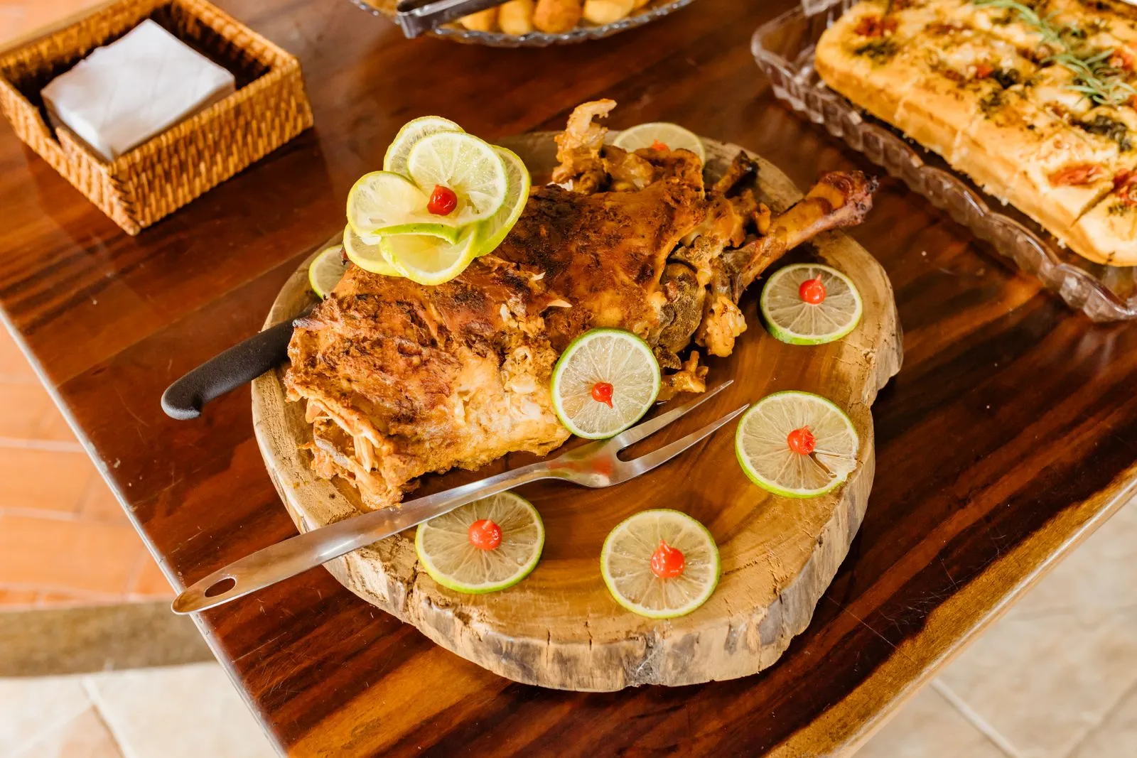 Delicious roasted lamb served with lime slices and garnishes on a wooden platter.